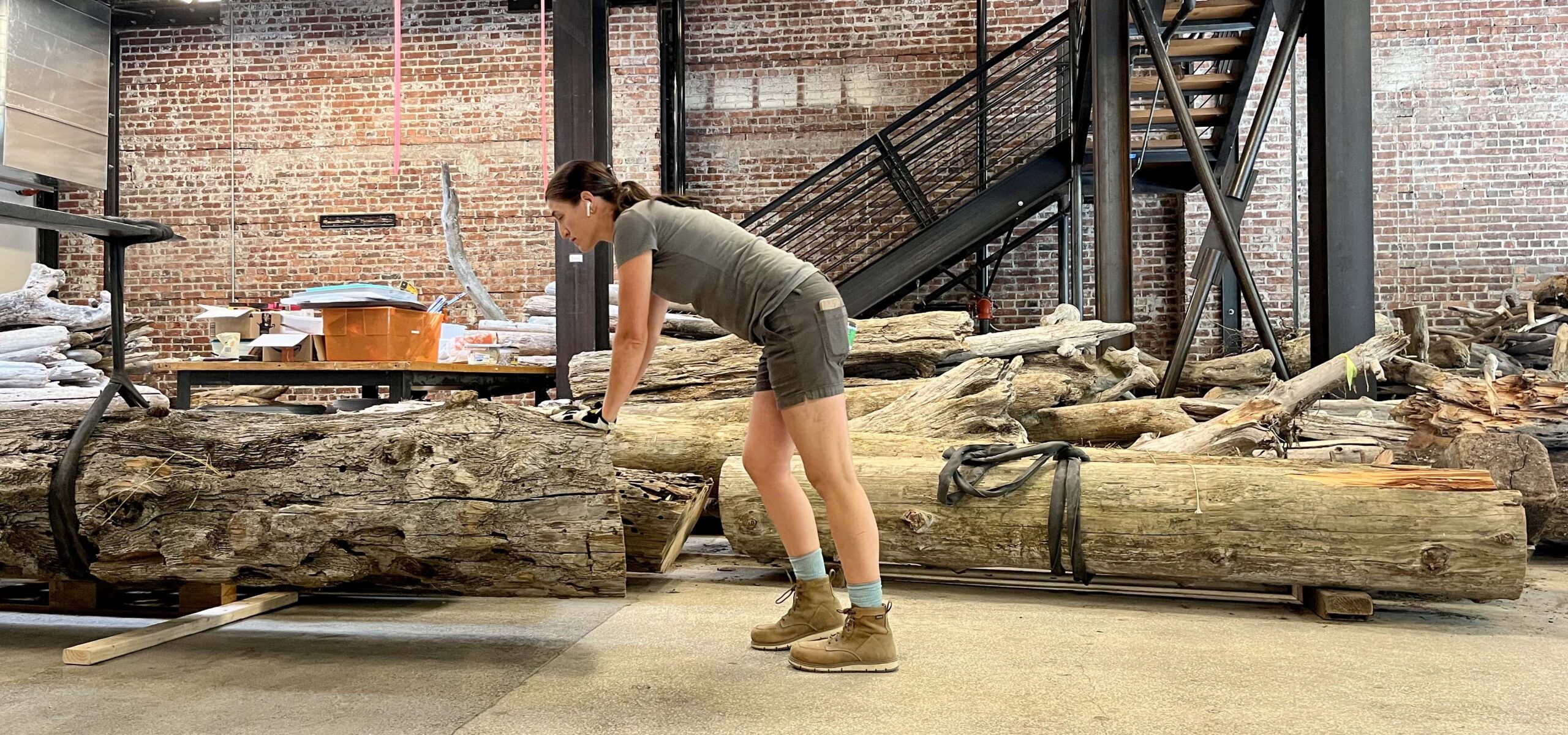 Artist, Stigora, pushing a driftwood log into place in a modern art installation.