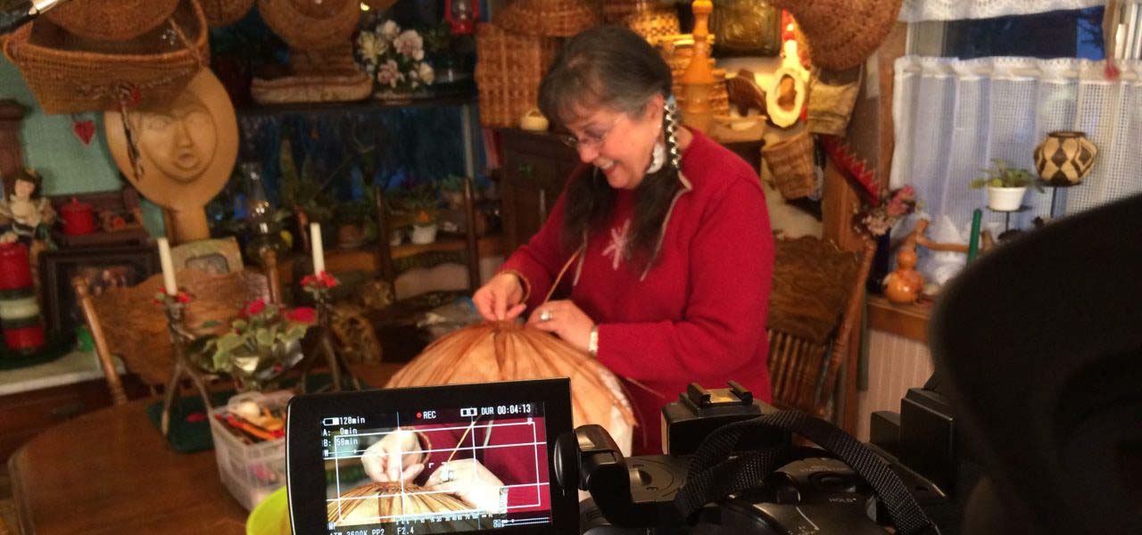 A woman being filmed while completing a craft.