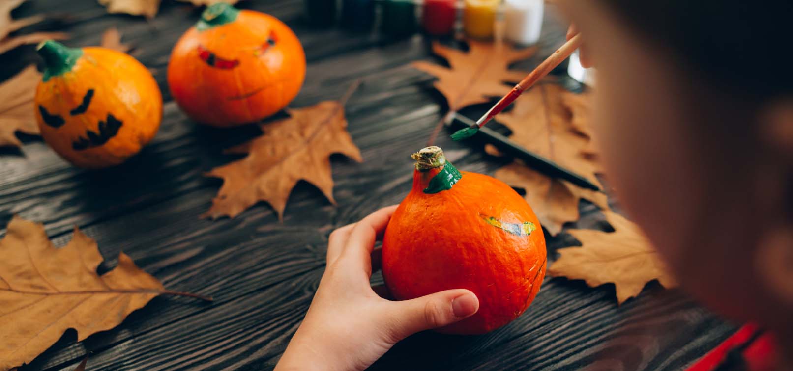 Kid painting mini pumpkins.