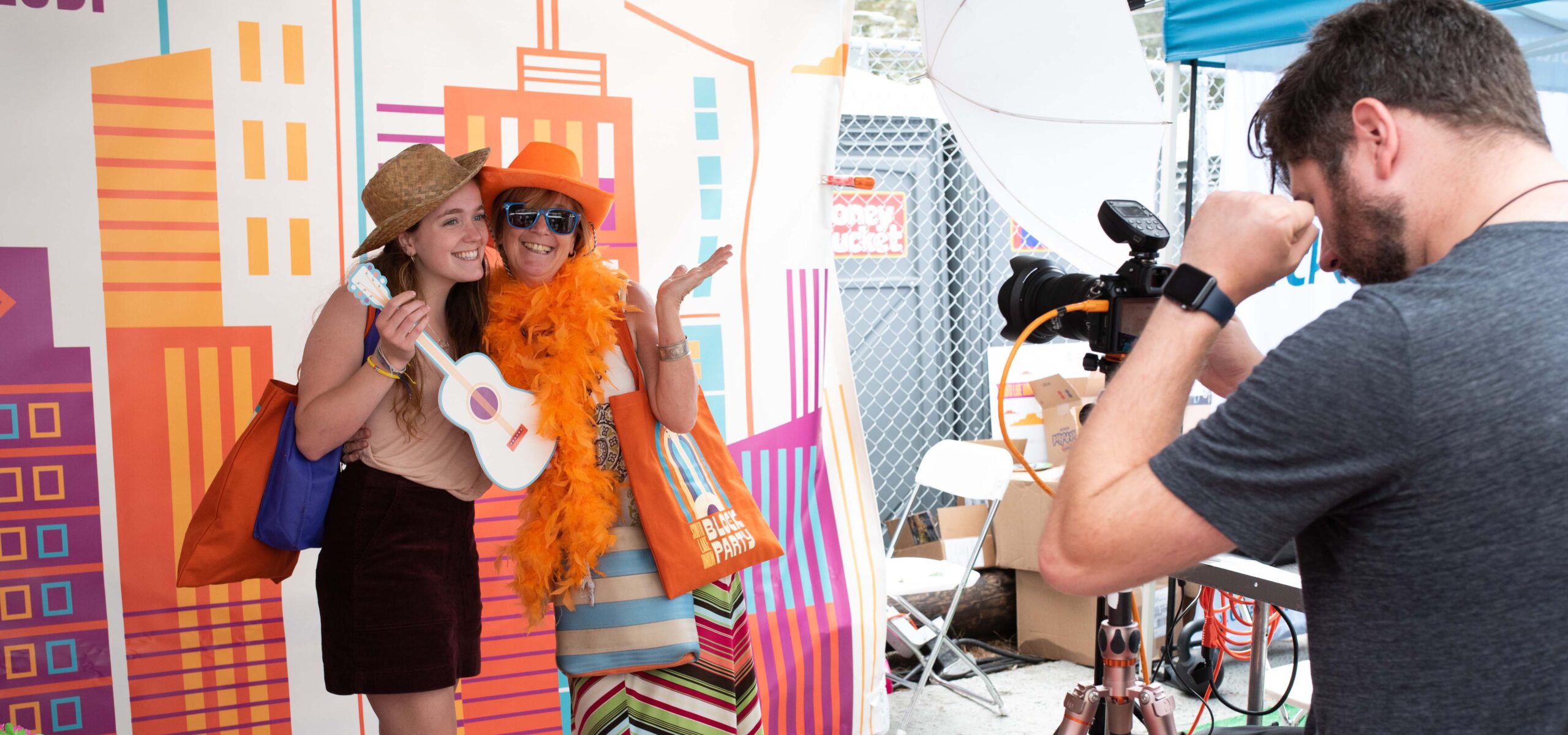 Photographer taking a photo of two women holding photo props at SLU block party.