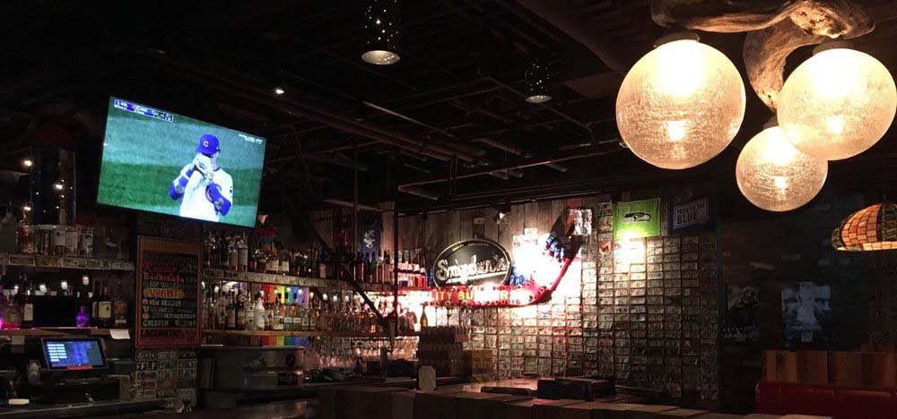 A row of taps below a couple TVs broadcasting a baseball game.