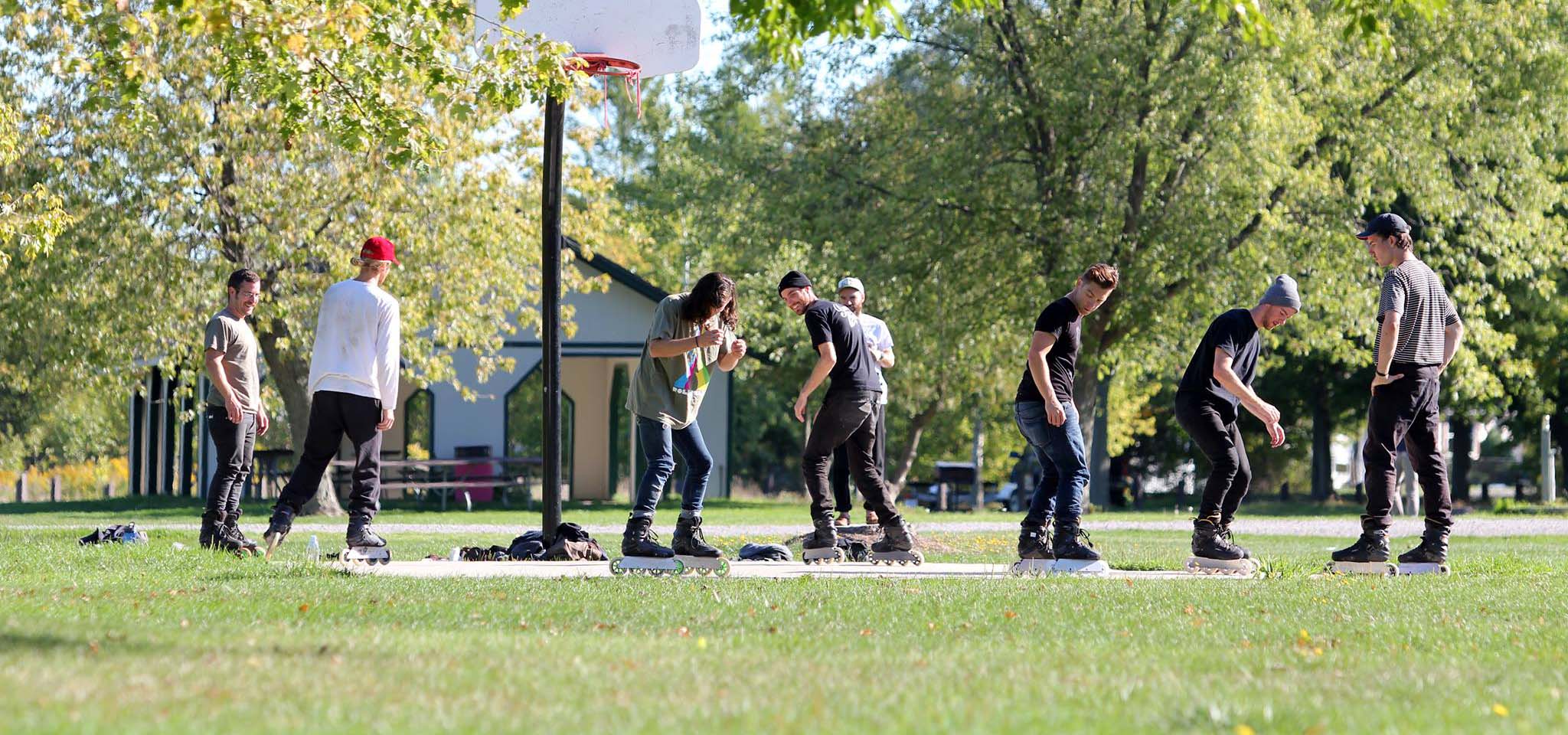 Group of people inline skating on a basketball court.