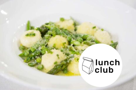 White plate filled with gnocchi, peas, and asparagus.