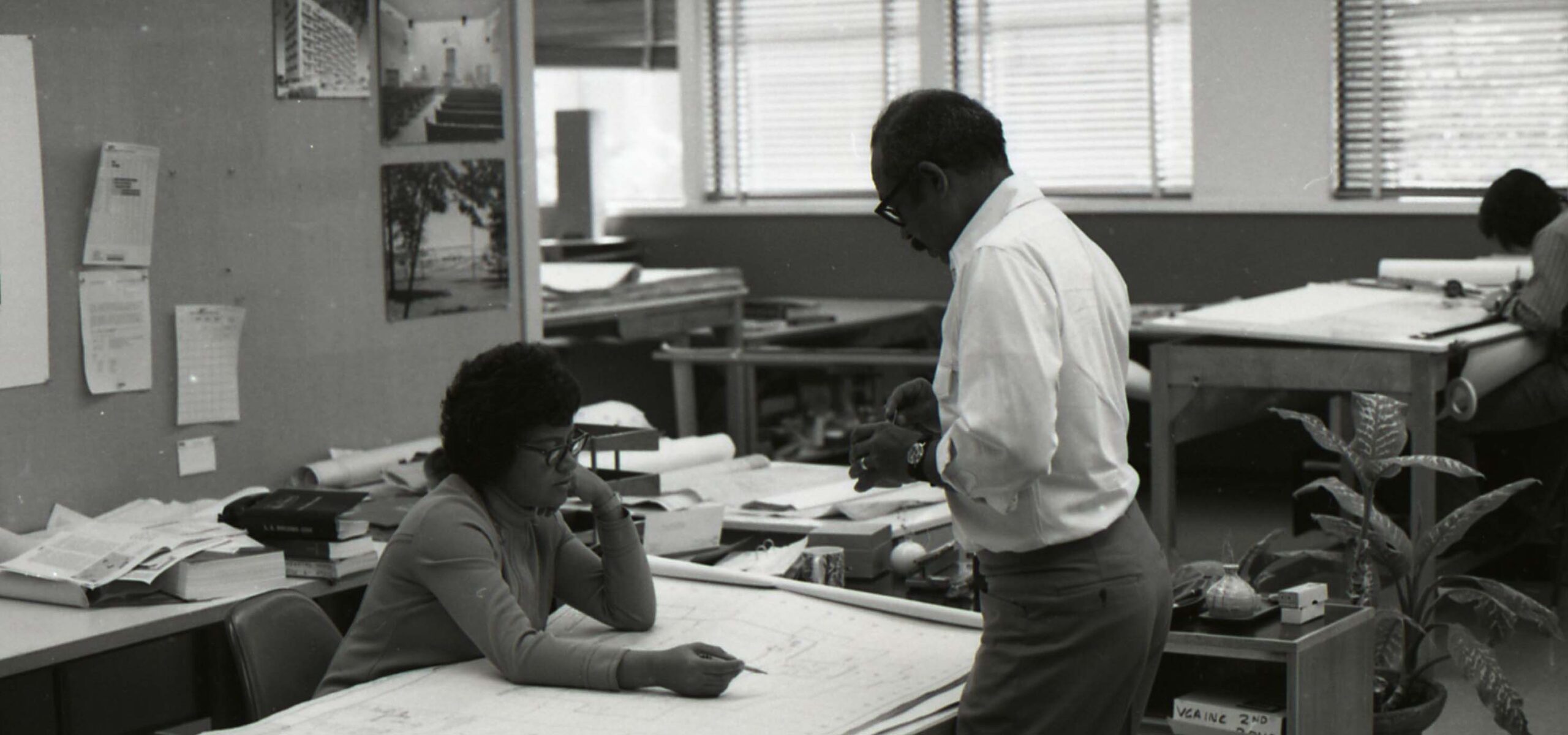 Two African-American architects looking at plans at a desk.