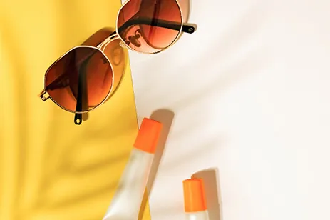 sunglasses and chapstick on yellow & white background