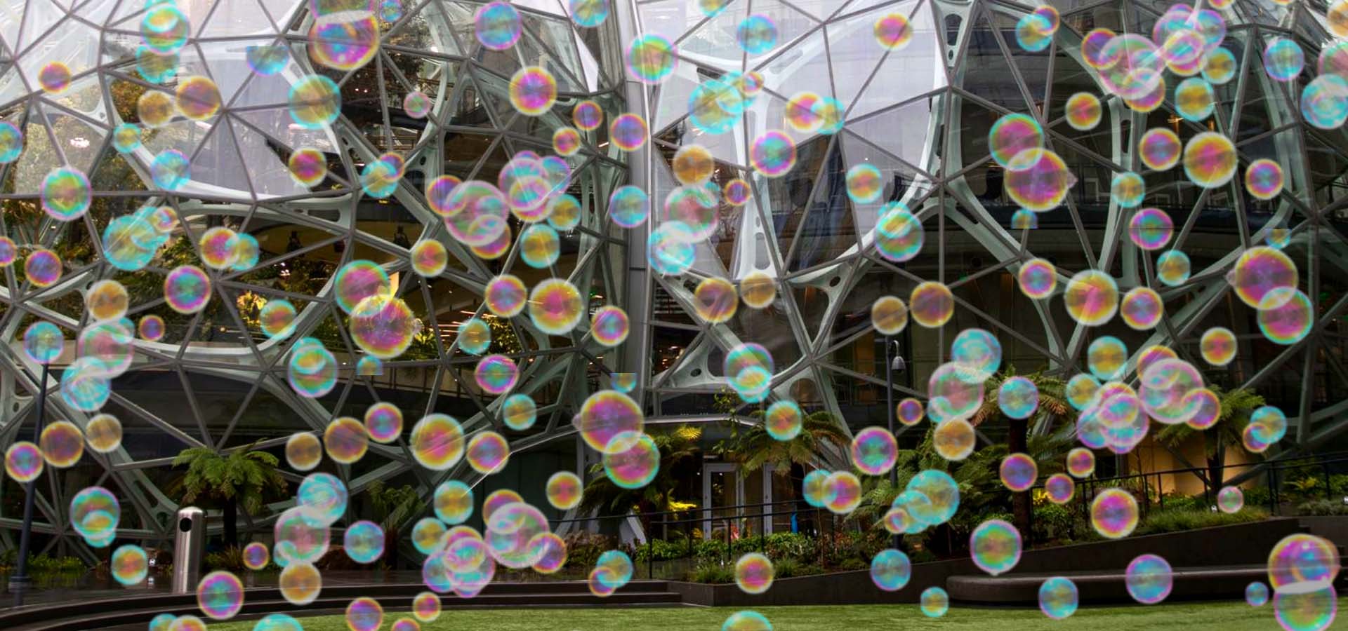 Bubbles floating in front of office buildings that are round/The Amazon Spheres.