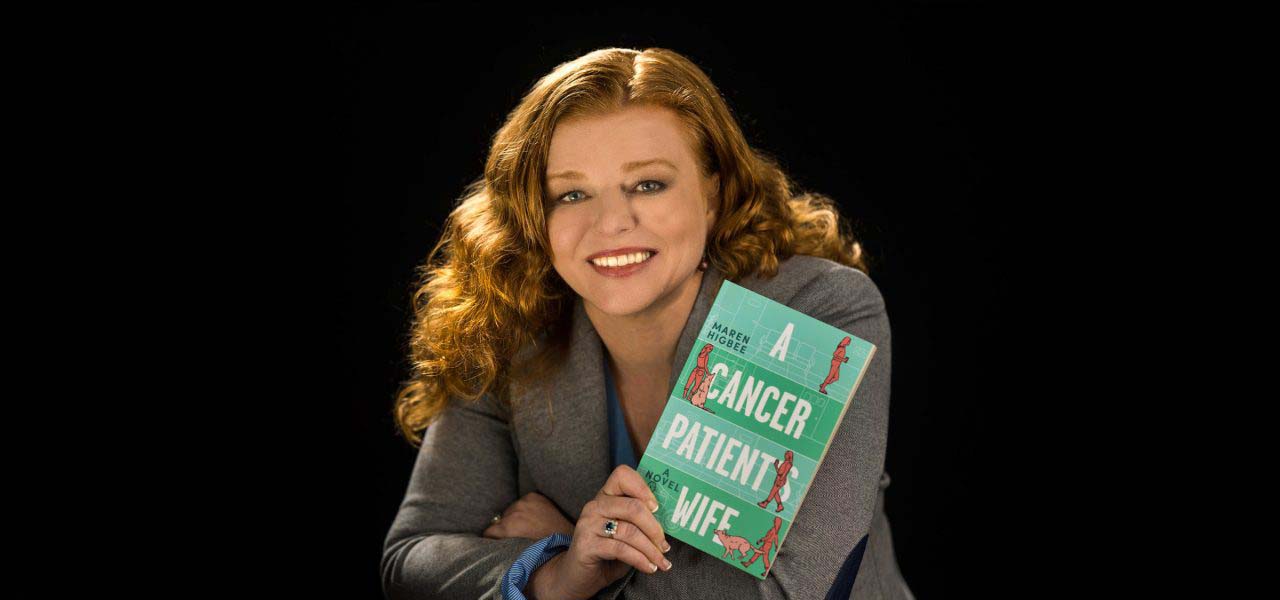 A redheaded woman holding up a blue book.