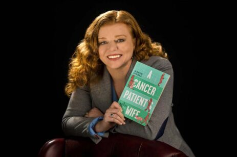A redheaded woman holding up a blue book.