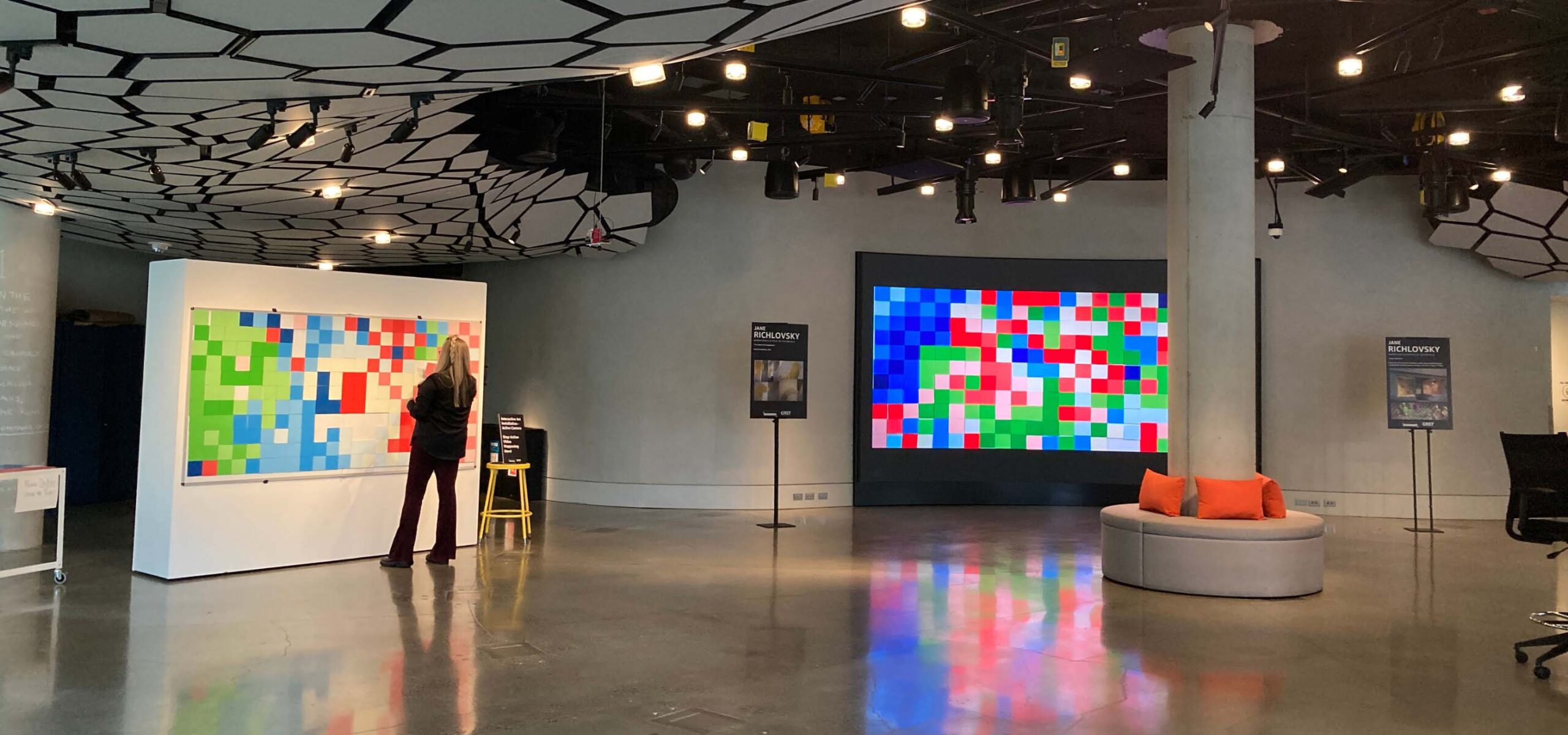 A woman standing in front of a giant pixel art display.