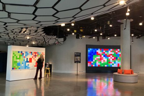 A woman standing in front of a giant pixel art display.