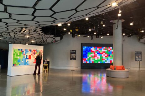 A woman standing in front of a giant pixel art display.