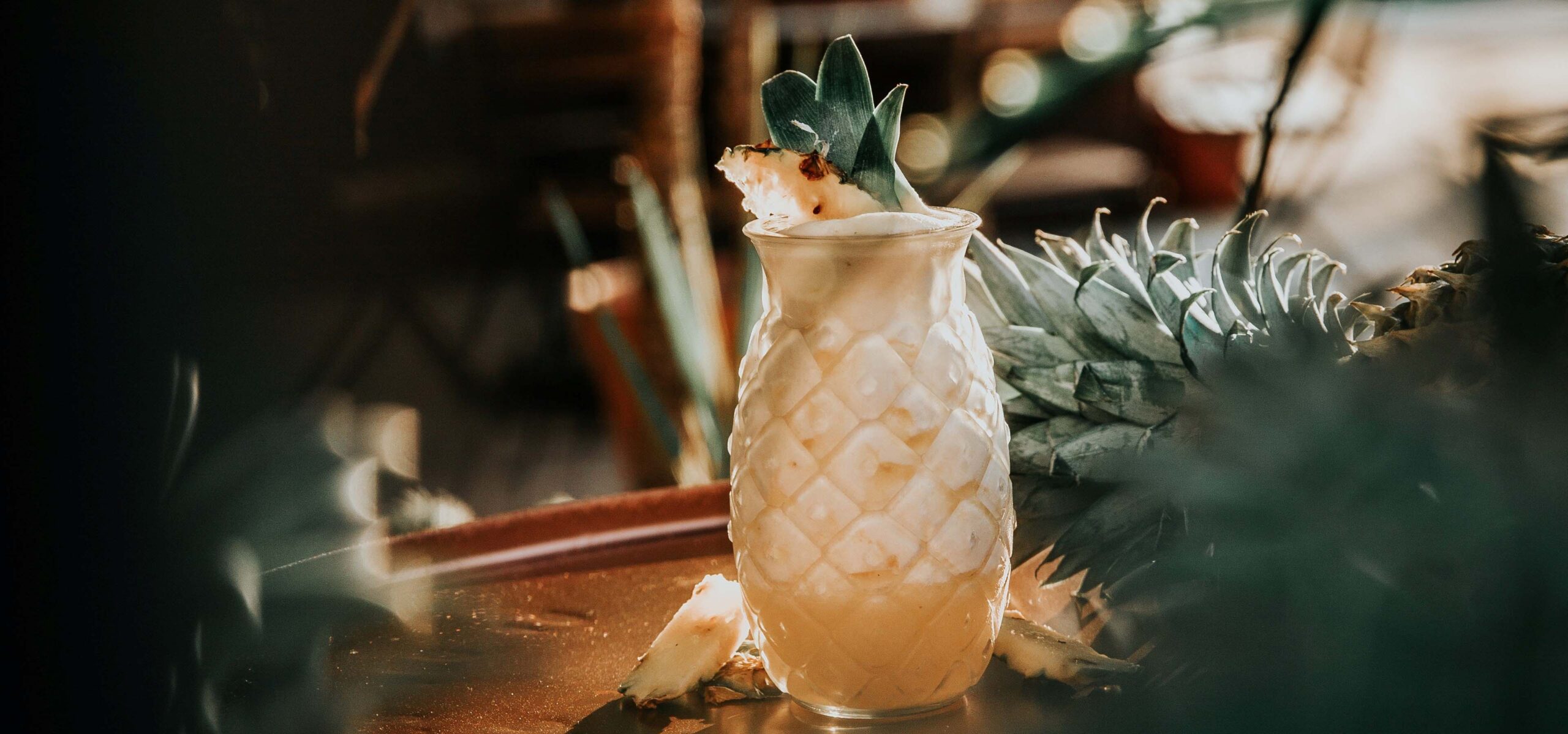 Cocktail in a pineapple shaped glass on a bar top.