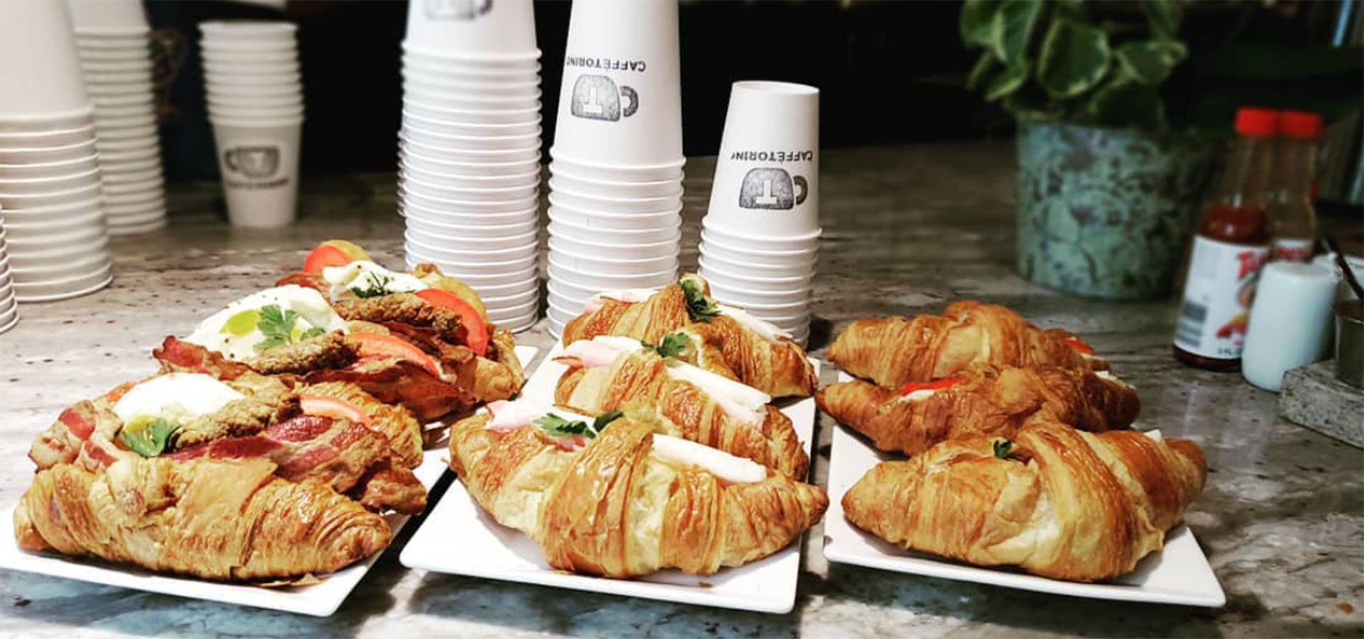 croissant sandwiches and coffee cups