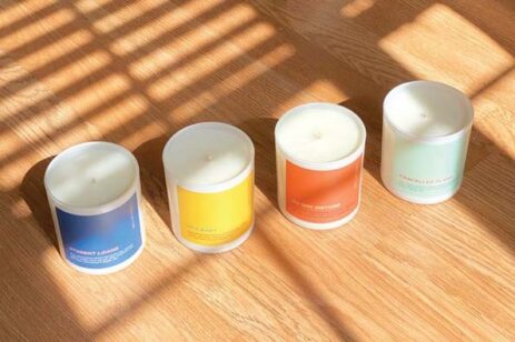 Four candles in a row on a floor with shadows and light.