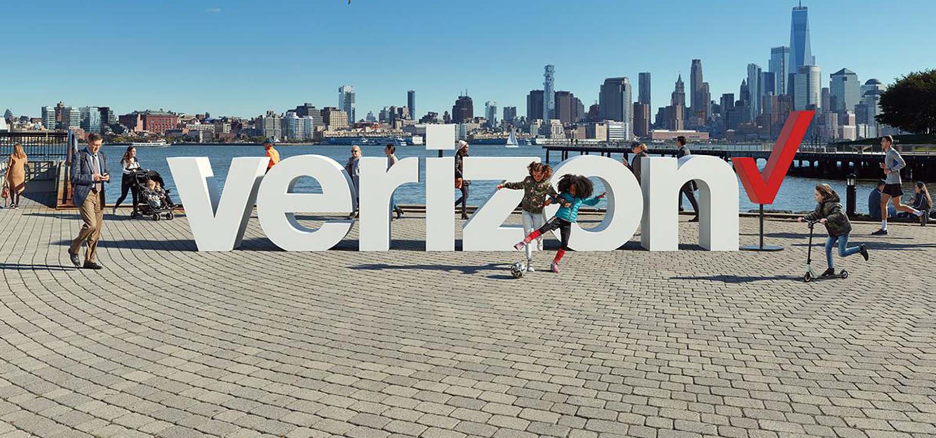 People playing on a waterfront with the Verizon logo installed as public art on the ground