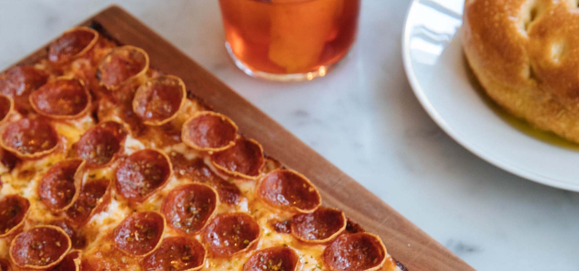 Table with pizza, beer, and an appetizer of bread.