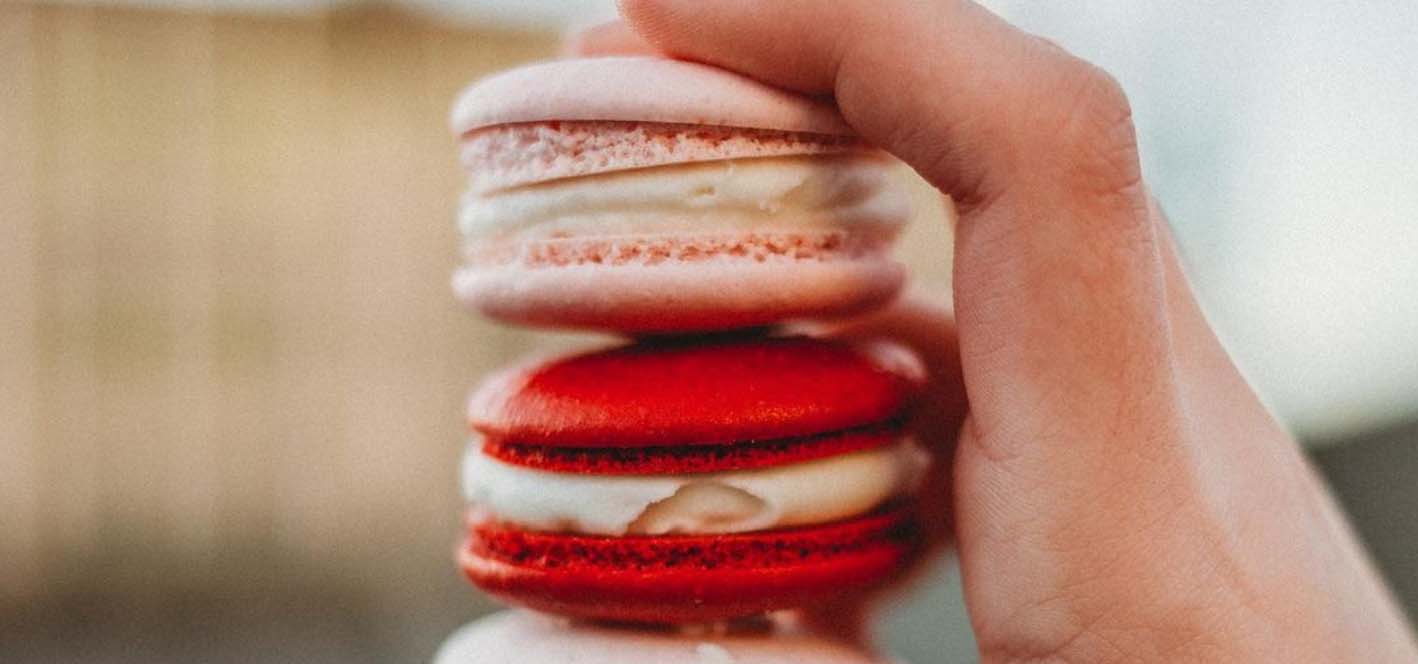 Hand holding pink and red macarons.
