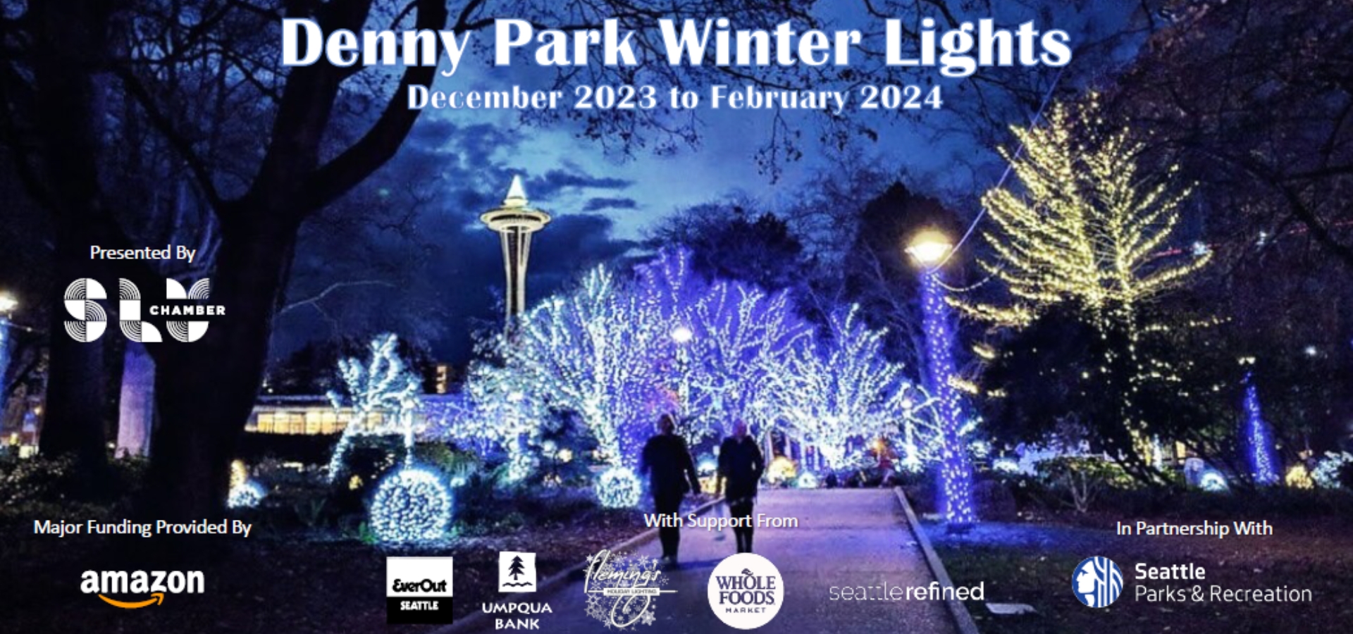 People walking through a park with holiday light on the trees.