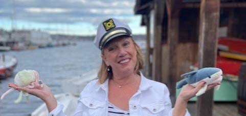 A woman wearing a sailor hat and holding sea creature toys.