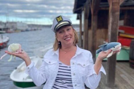 A woman wearing a sailor hat and holding sea creature toys.
