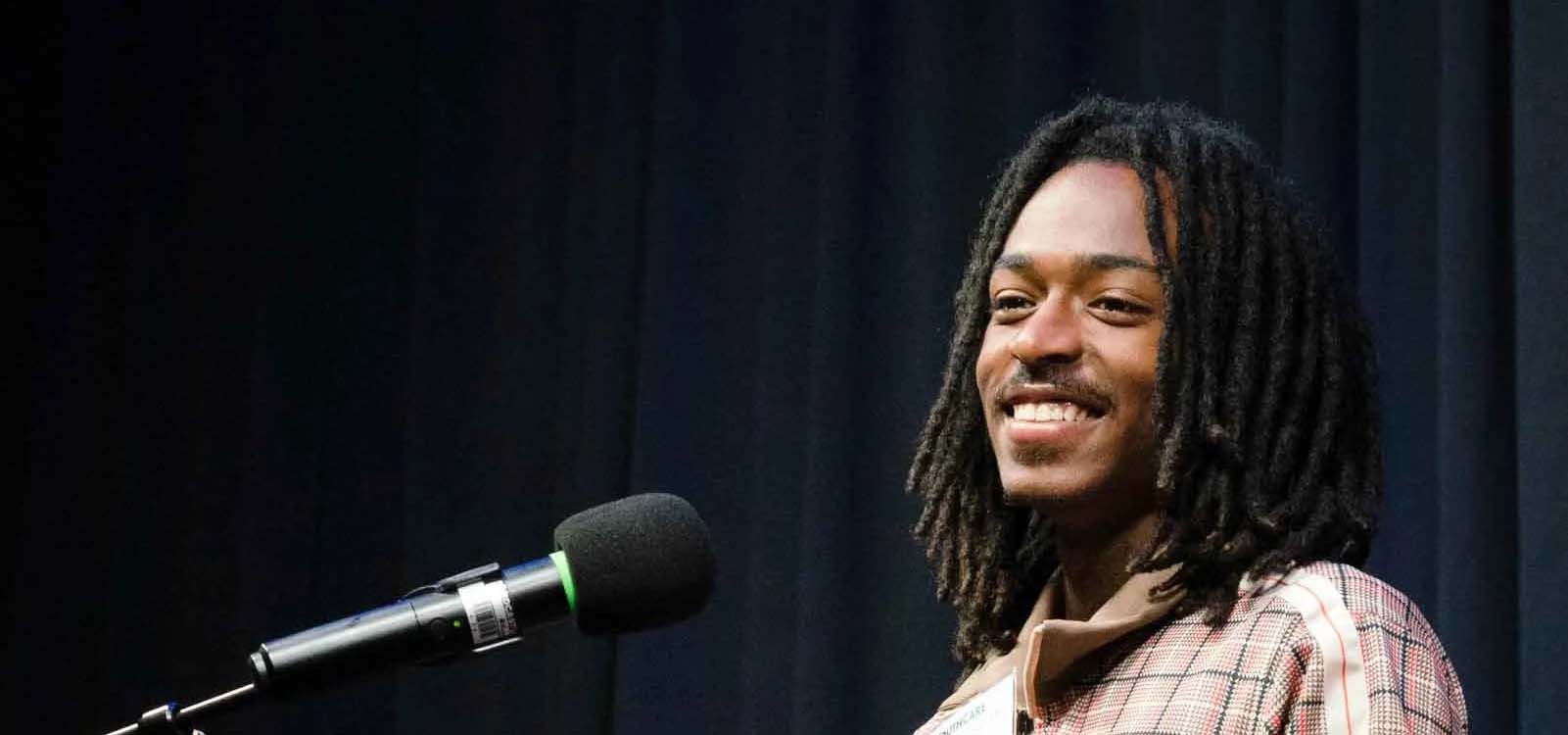 Man speaking and smiling at a podium with a microphone.