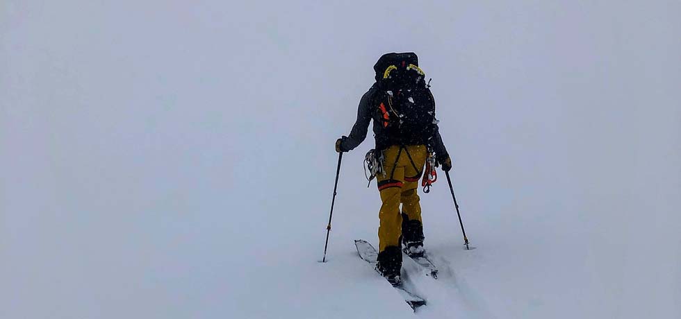 Backcountry skier trekking through a snowy plain.