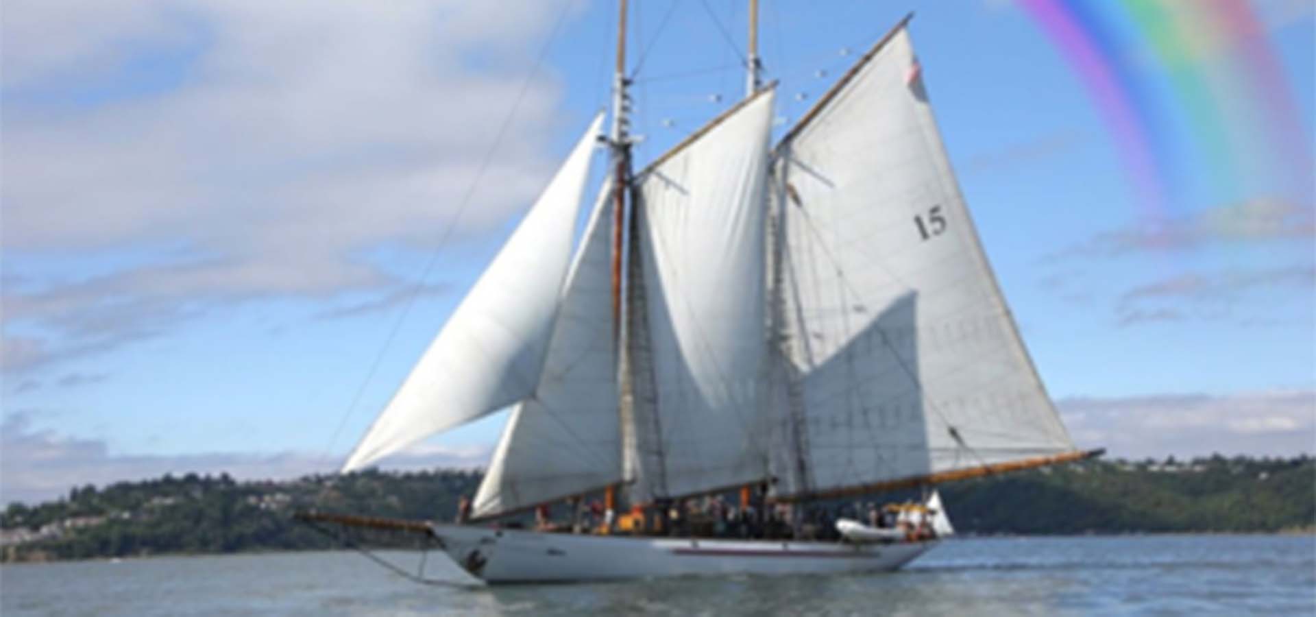 Sailboat with rainbow overhead.