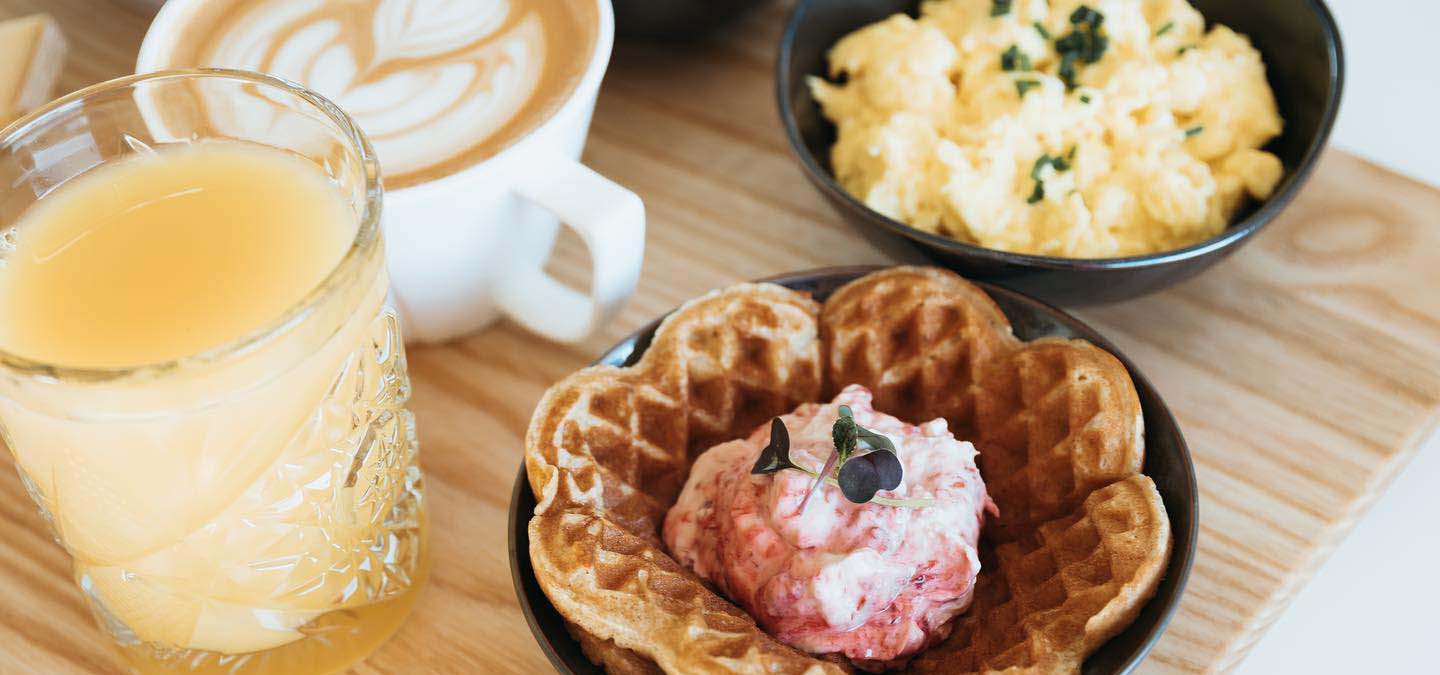 Selection of brunch foods like eggs, waffles, orange juice, etc.