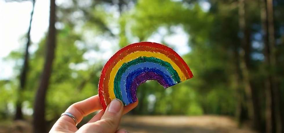 Woman holding a toy rainbow in the forest.