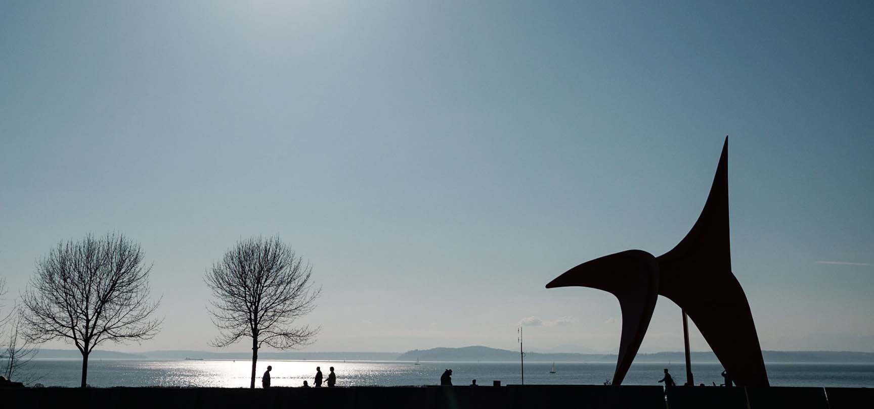 Horizon photograph with ocean, trees, people & outdoor sculpture art.