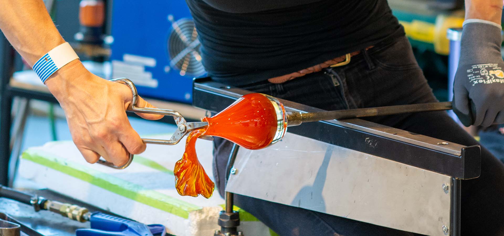 Glassworker creating a red votive holder.