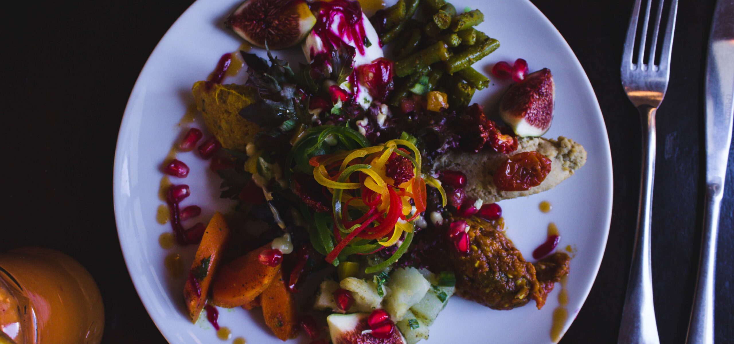 White plate with colorful vegetables, meats, and sauce.