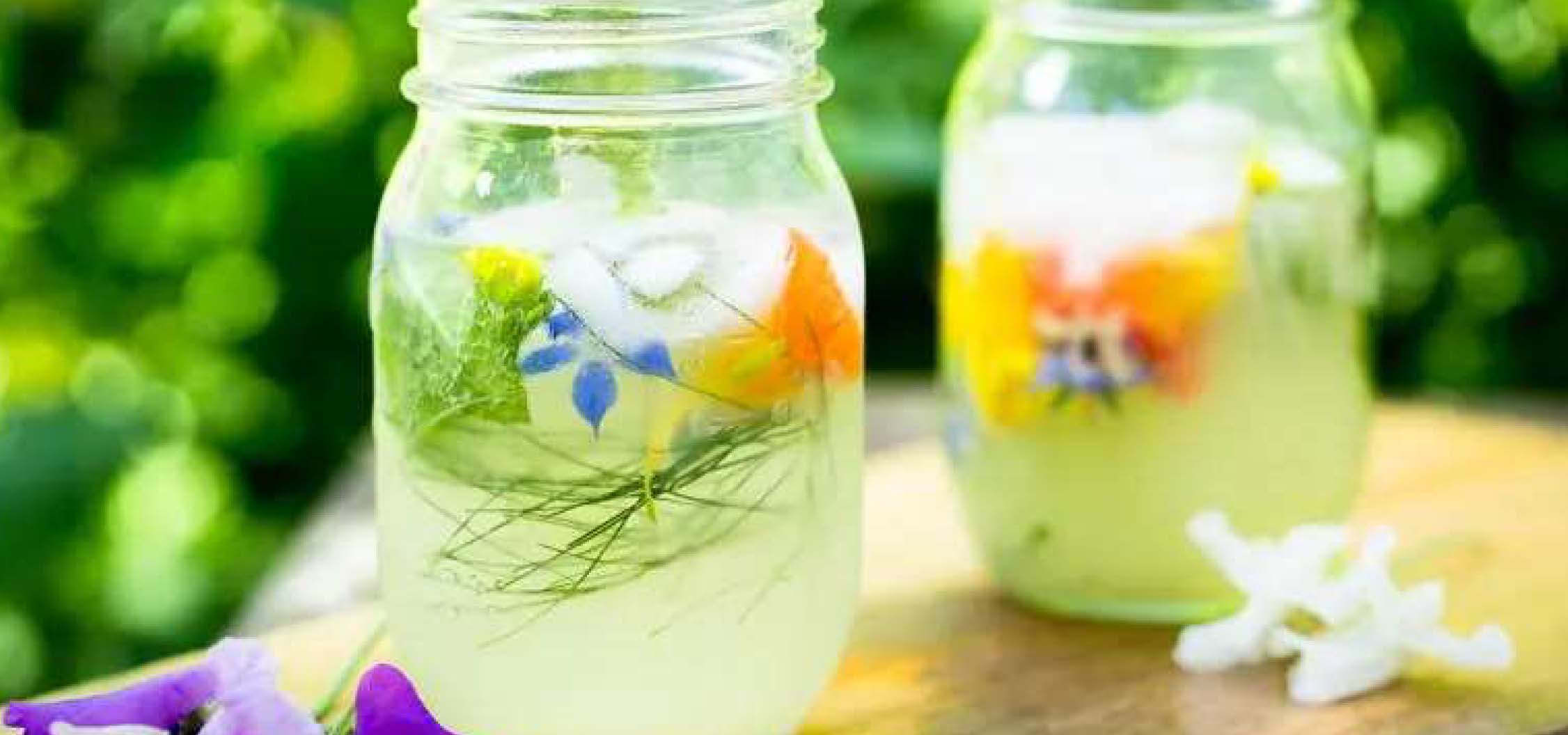 Two drinks mixed in mason jars, garnished with spring flowers.