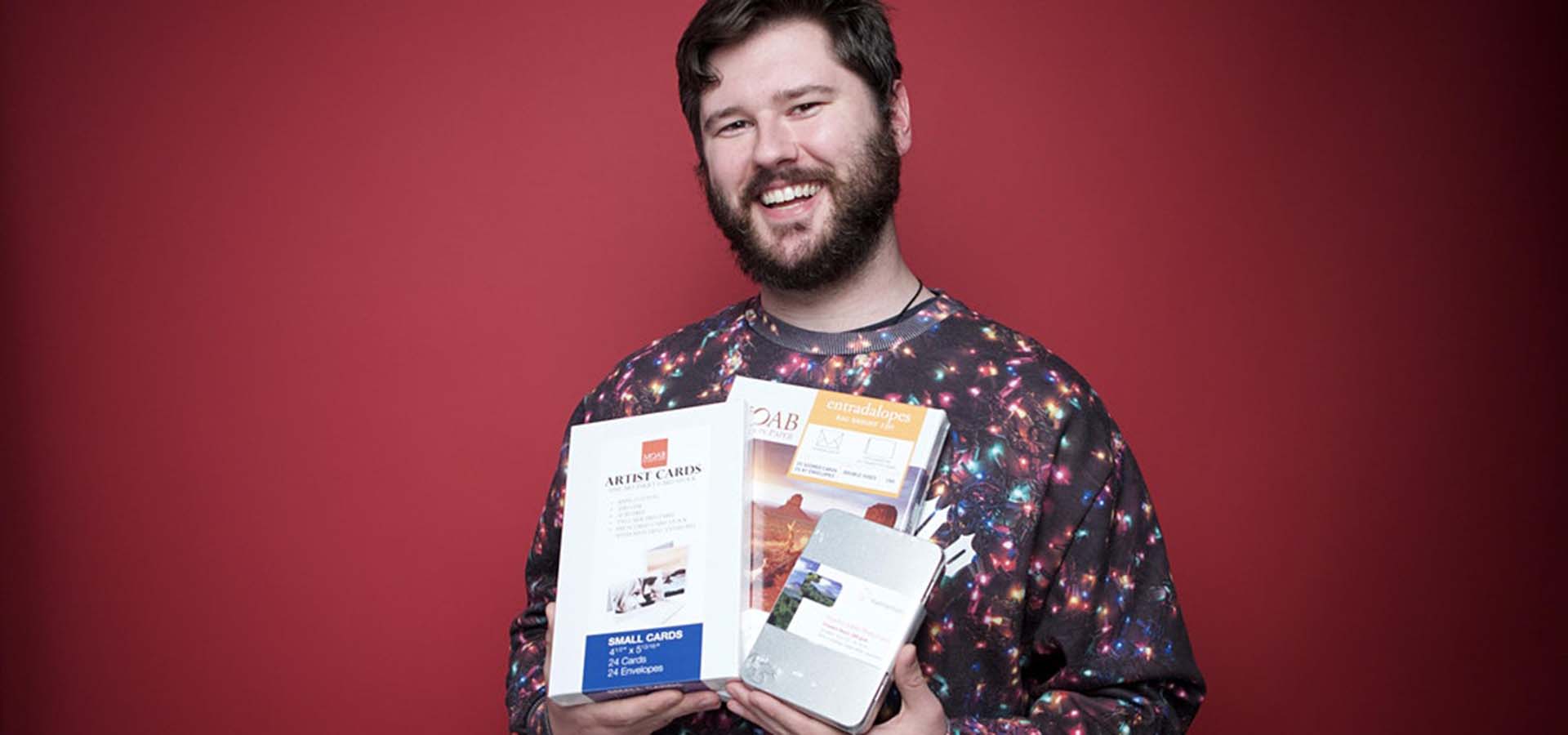 Man with ugly Christmas sweater on holding up photography books.