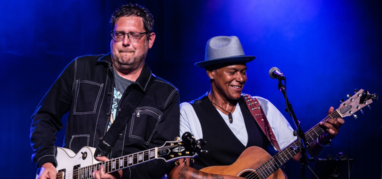 Two men playing guitars on stage.