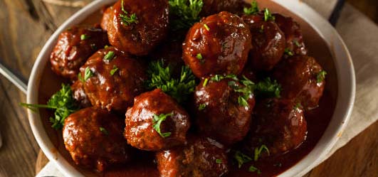 White dish filled with saucy meatballs.