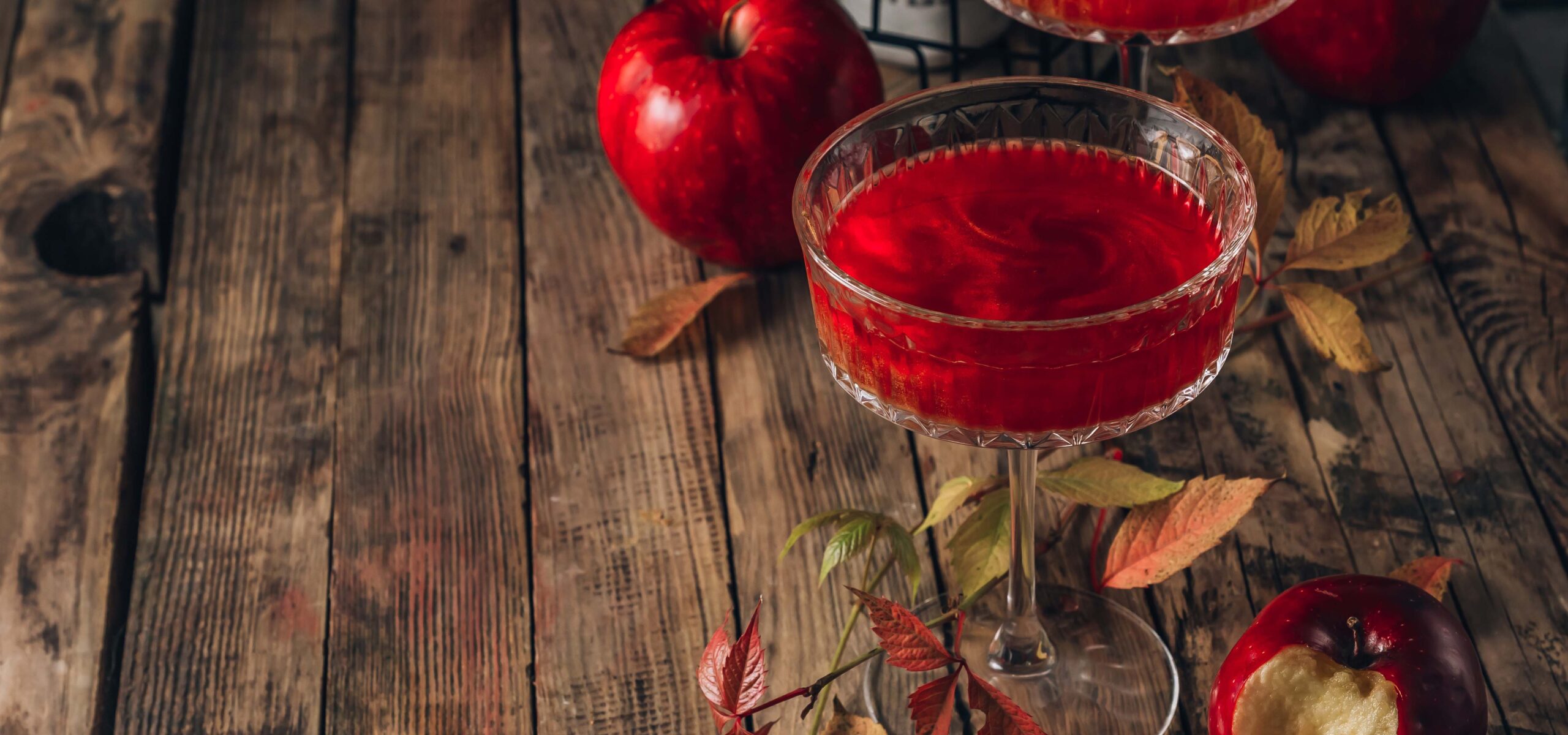 Wood table with a red cocktail drink on it.