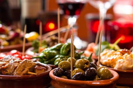 Array of small dishes filled with tapas like olives and peppers.