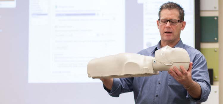 Man holding a CPR maniquin.