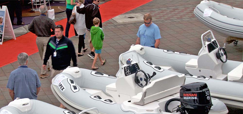 People viewing inflatable boats on a pier.